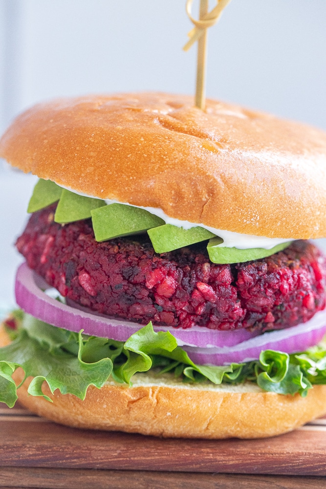 close up of a vegan beet burger in a bun with avocado