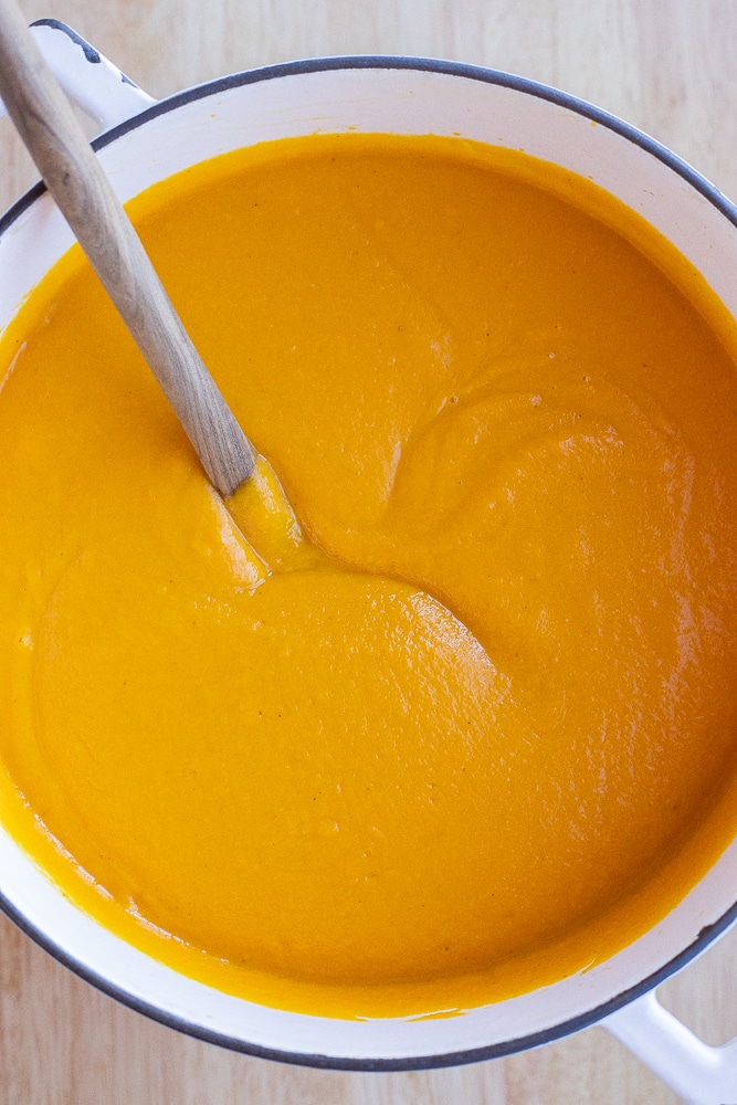 creamy roasted root vegetable soup in a pot with a spoon