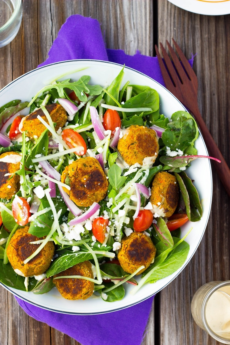 a bowl of roasted carrot falafel salad with feta cheese, onion and tomato