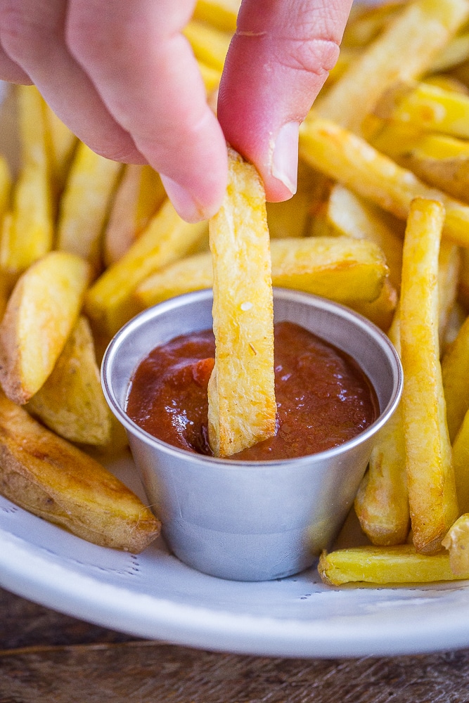 a crispy baked French fry being dipped into ketchup