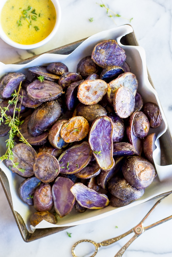 a dish full of roasted purple potatoes with lemon dijon dressing