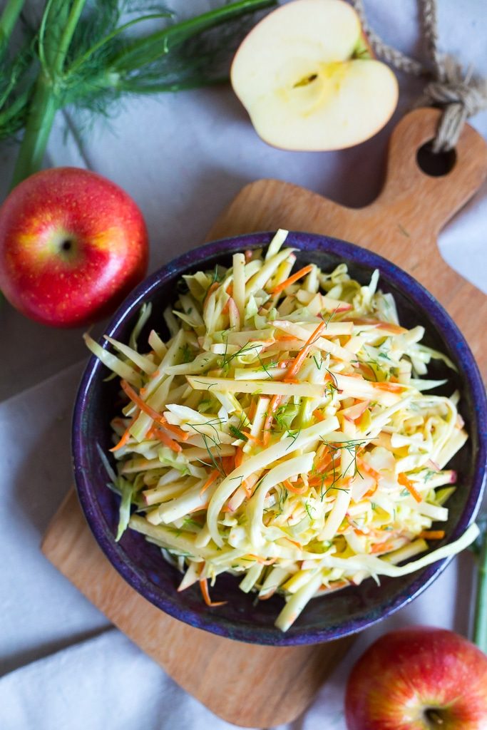 a bowl of apple and fennel slaw on a cutting board