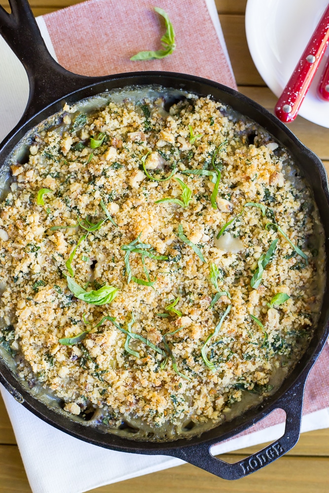 cast iron skillet of vegan scalloped potatoes with pesto bread crumbs