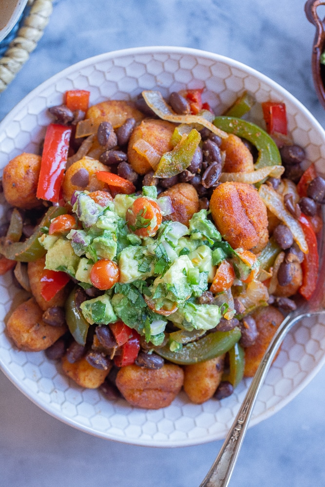 close up of a bowl of gnocchi with peppers and onions