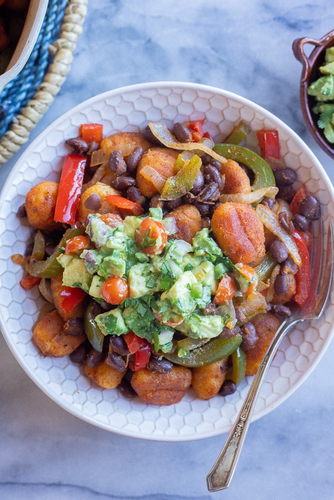 a dinner bowl full of fajita gnocchi skillet with avocado salsa