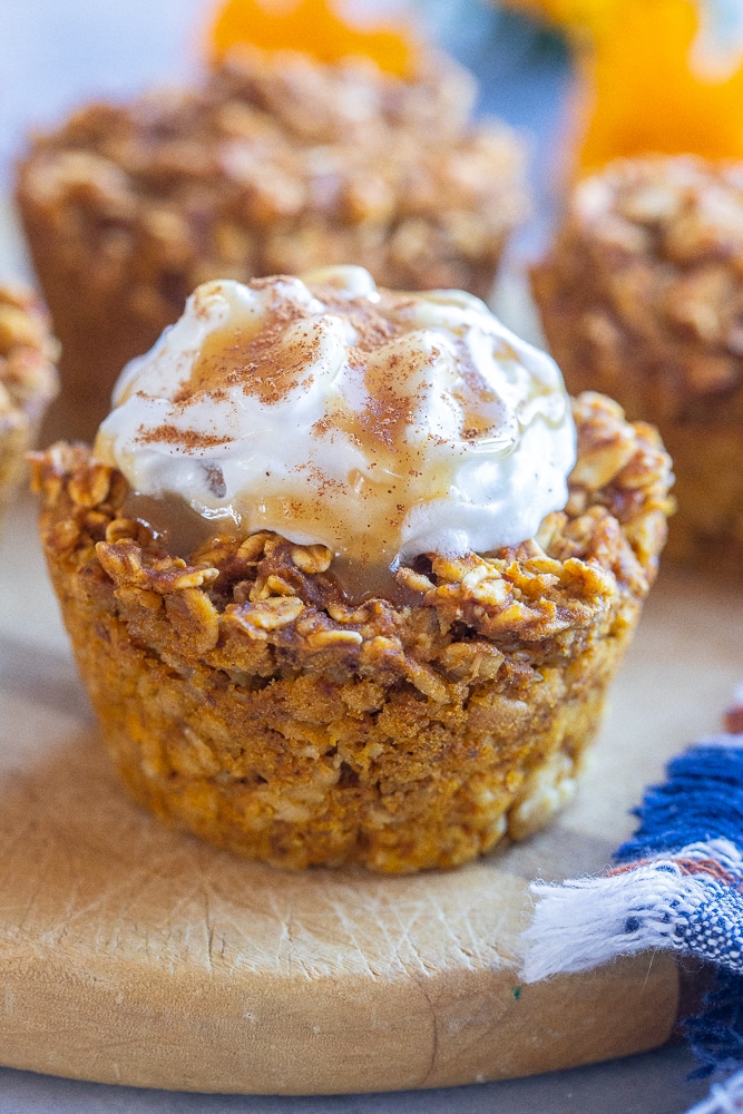 close up of a pumpkin pie baked oatmeal cup topped with whipped cream and caramel sauce