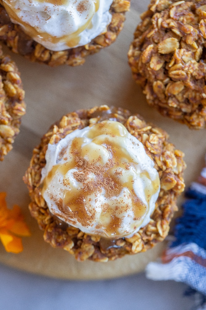close up of a pumpkin pie oatmeal cup topped with whipped cream and caramel
