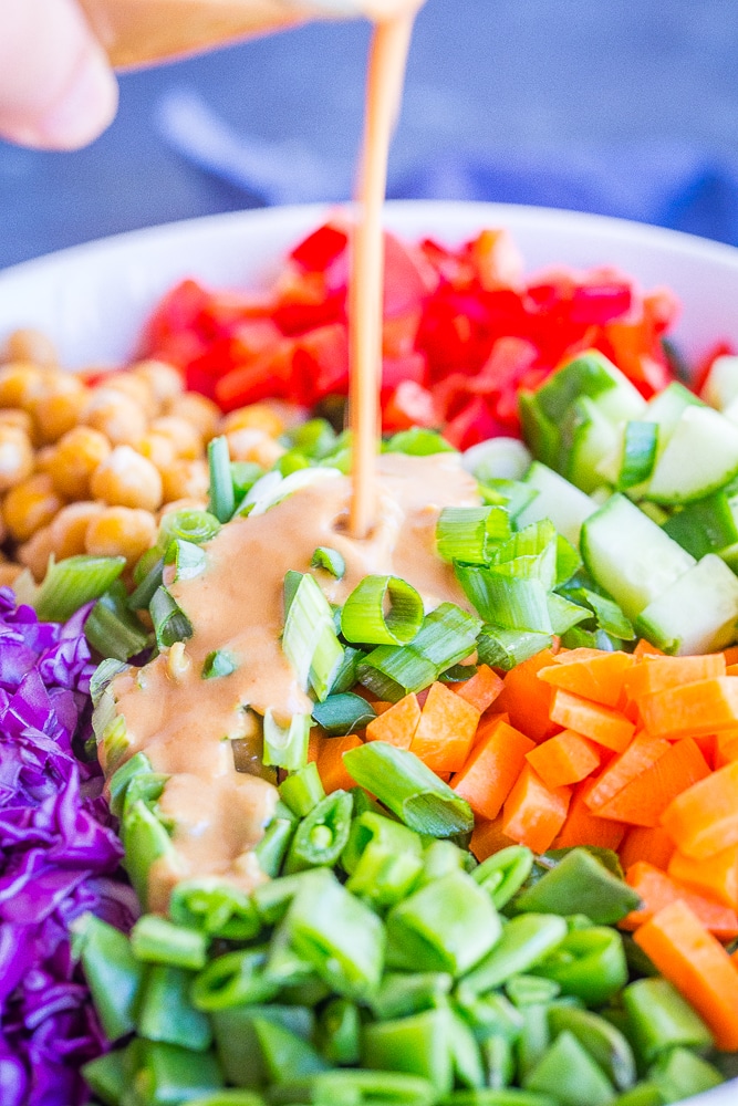 Salad dressing being poured over the Asian Chickpea Chopped Salad