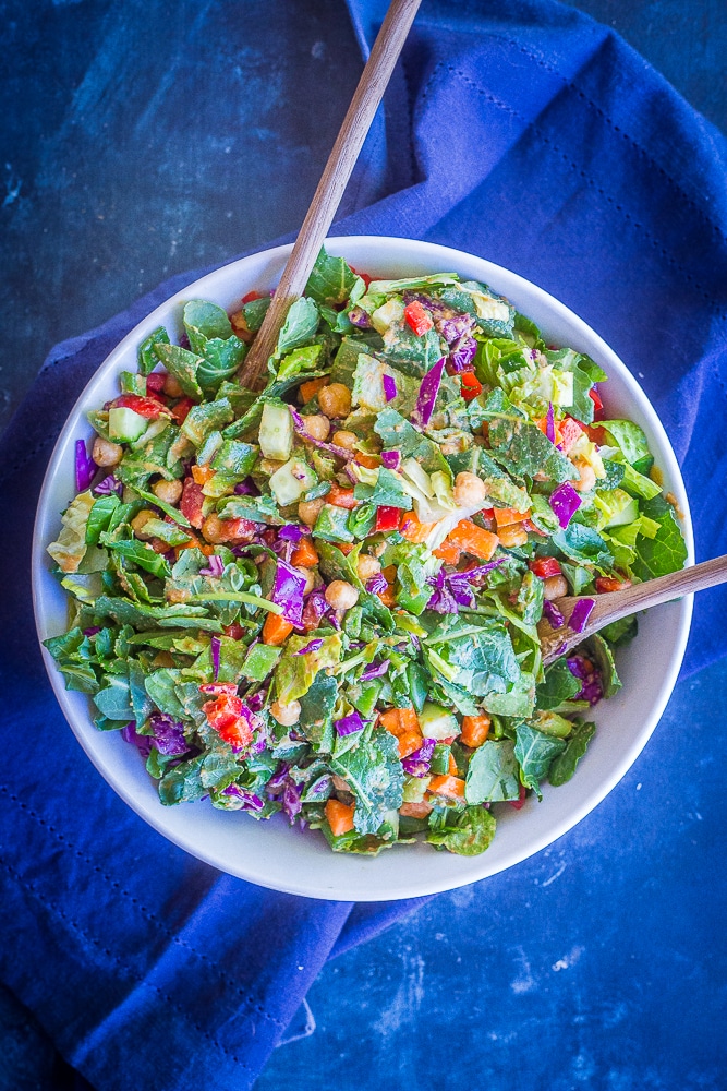 The Asian Chickpea Chopped Salad in a large mixing bowl with two wooden spoons. Salad is mixed up.