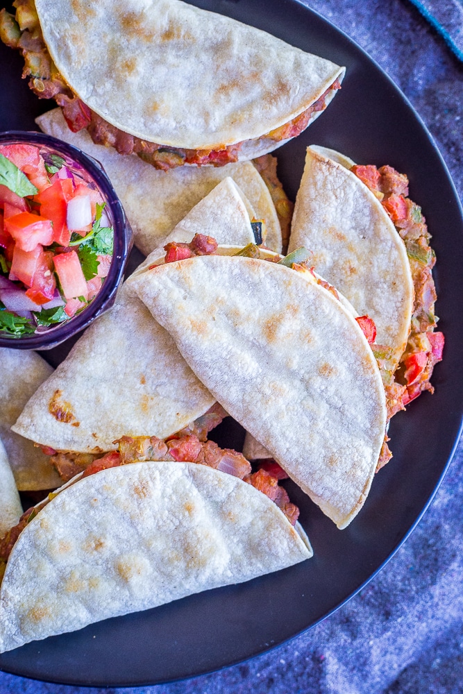 Crispy baked tacos with summer vegetables on a plate with a side of salsa