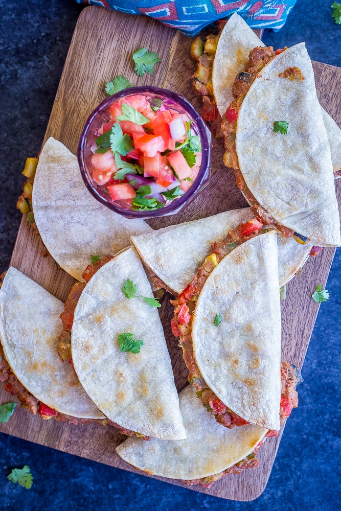 Crispy baked tacos with summer vegetables on a cutting board with a side of salsa