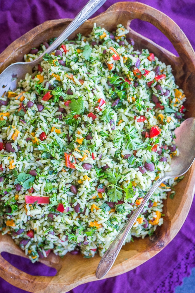 A big bowl of Green Rice with Black Beans and Sweet Potato with two serving spoons in it