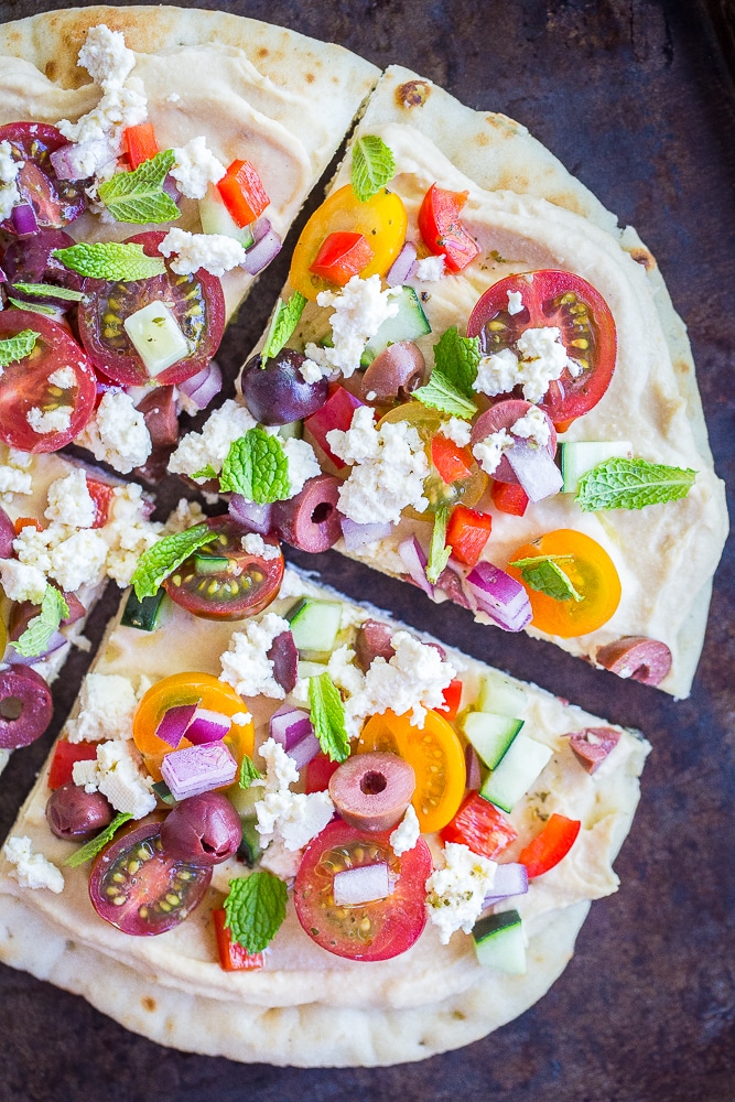 A no cook Mediterranean Hummus Pizza cut into four slices on a sheet pan