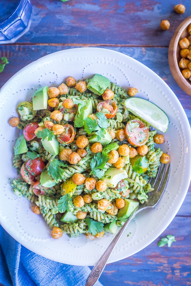 A bowl of Southwestern Pesto Pasta with Crispy Chickpeas with a glass of water and a bowl of crispy chickpeas