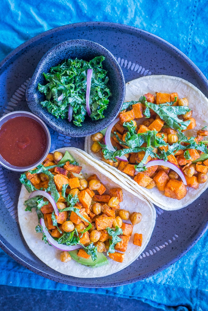 Sweet Potato and Chickpea Tacos on a plate with kale slaw and hot sauce