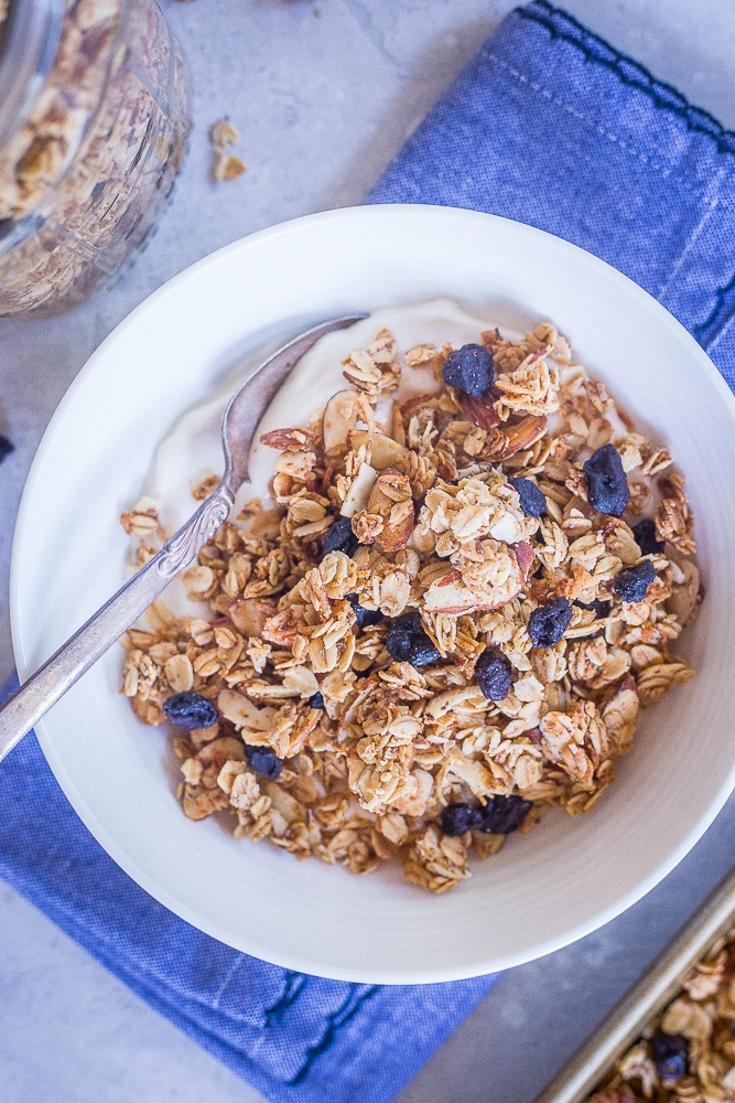 A bowl of Homemade Blueberry Almond Granola with yogurt on a blue napkin