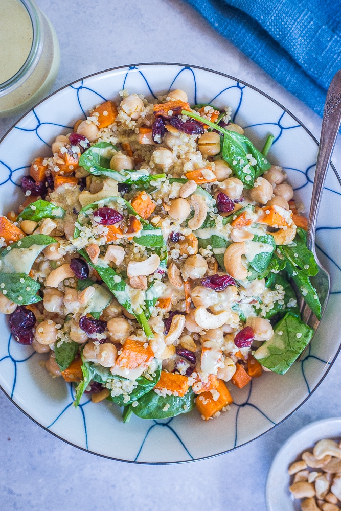 A large bowl of Quinoa Chickpea Sweet Potato Salad on a table with a jar of dressing.