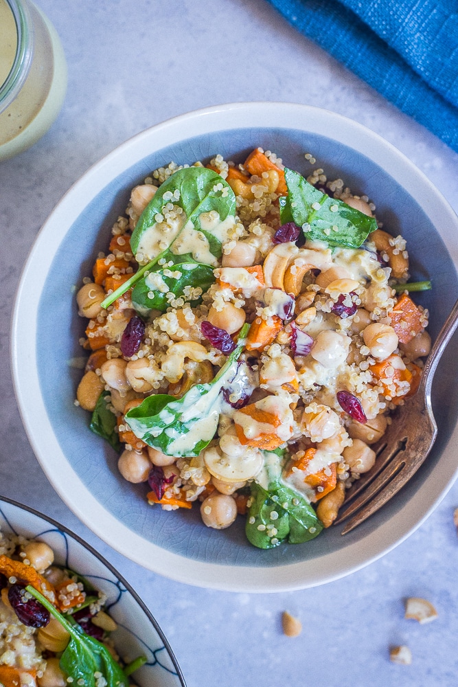 A bowl of Quinoa Chickpea Sweet Potato Salad with a blue napkin and fork