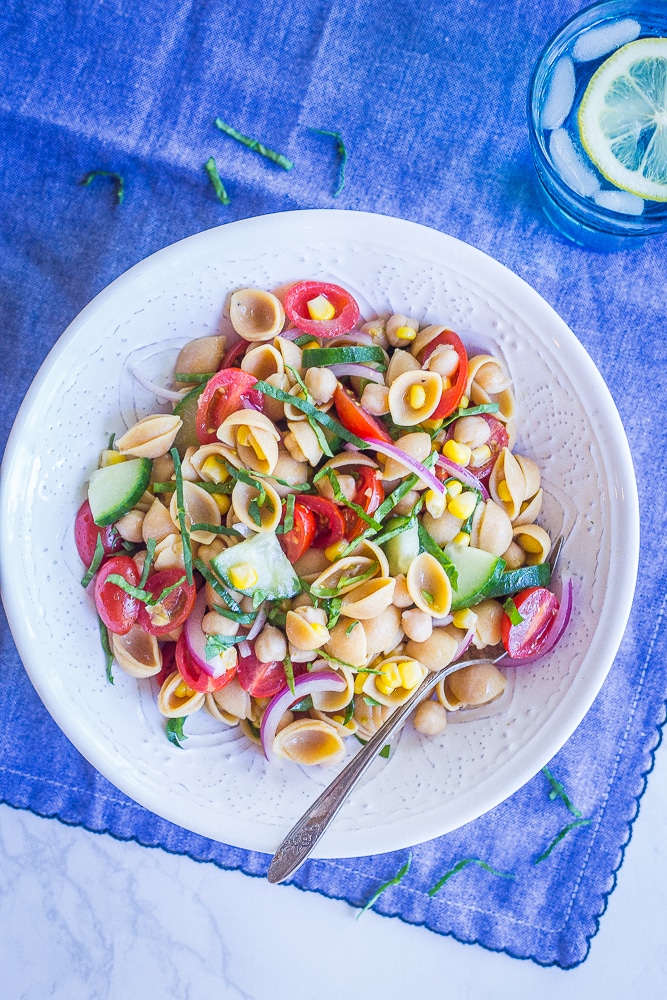 Bowl of summer vegetable pasta salad on a blue tablecloth