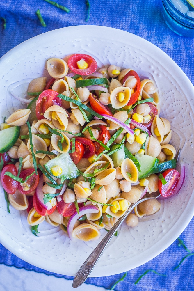 Bowl of summer vegetable salad with chickpeas on a blue tablecloth