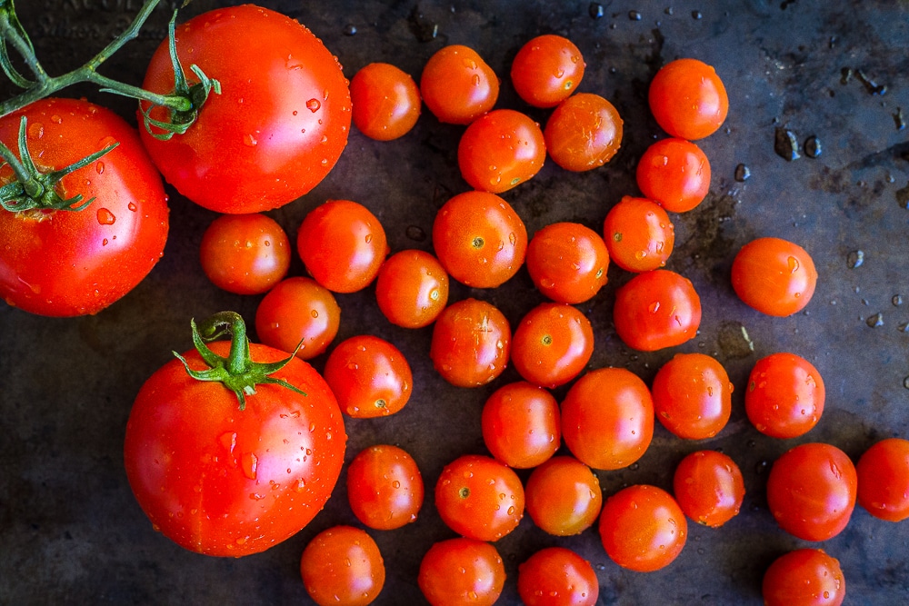 Cherry tomatoes and regular tomatoes on a dark background. Chunky Cherry Tomato Gazpacho ingredients