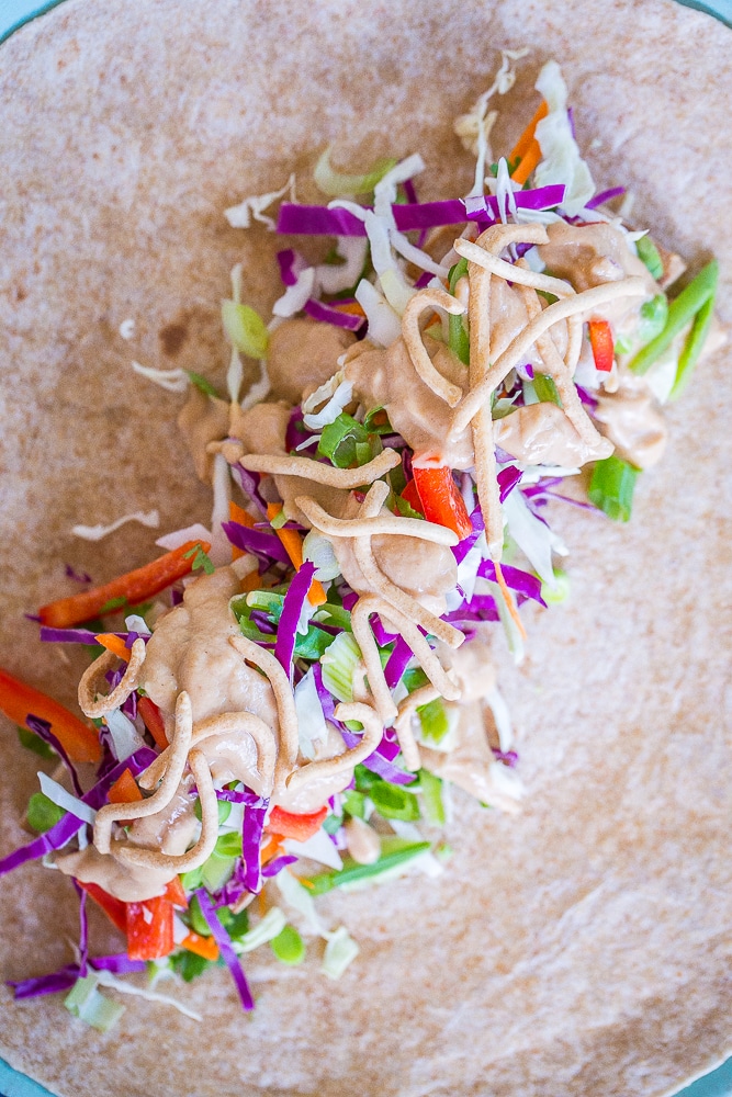 A open Crunchy Asian Tofu Peanut Wraps on a plate with all the filling showing.
