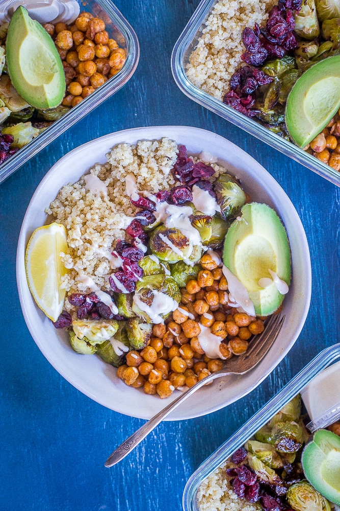 Bowl of Roasted Brussels sprout and Chickpea Meal Prep Bowls surrounded by three meal prep containers full.