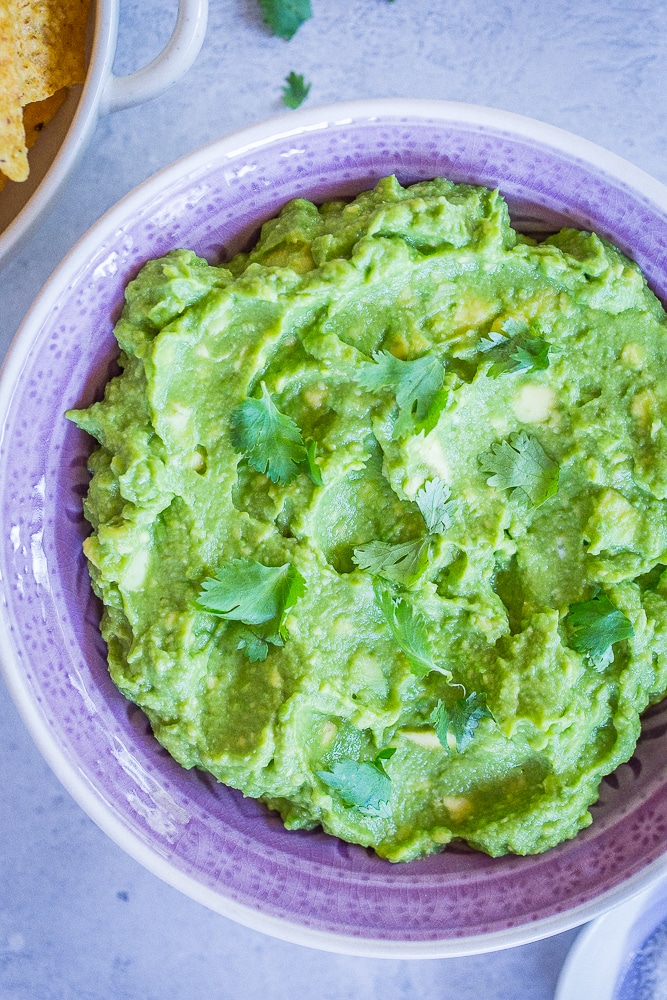 A bowl of The Best Easy Guacamole Recipe with a side of chips