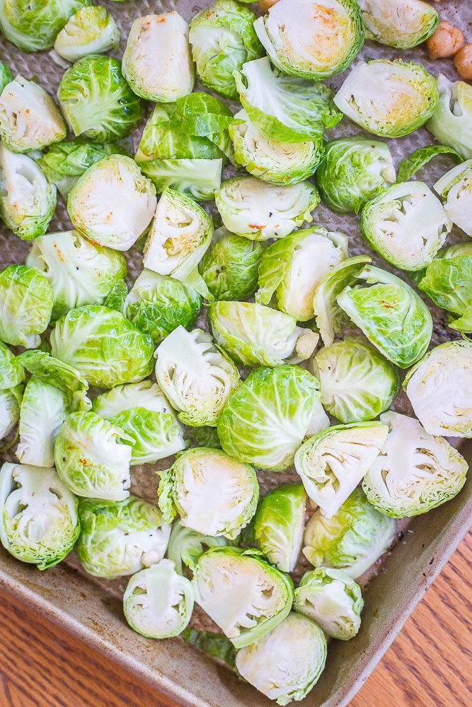 A tray of uncooked Brussels sprouts with seasoning on them. Best Simple Roasted Brussels sprouts