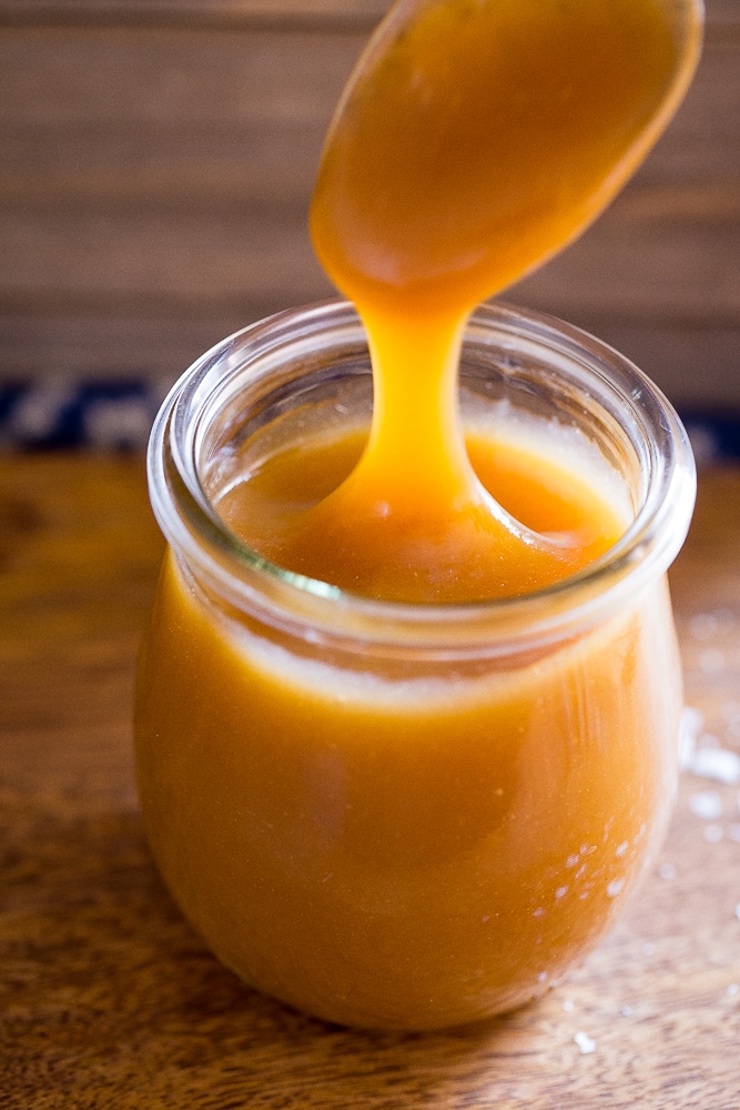 Easy Vegan Caramel Sauce in a jar with a spoon dipping into it
