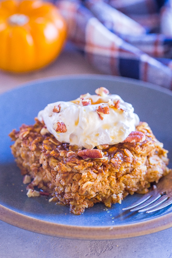 Slice of Make Ahead Pumpkin Pie Baked Oatmeal on a plate with whipped cream on top