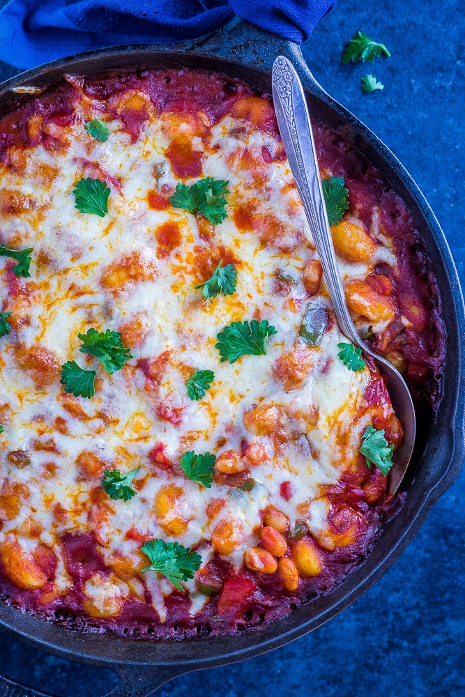30 Minute Gnocchi Pizza Bake with White Beans on a black background with a spoon in it