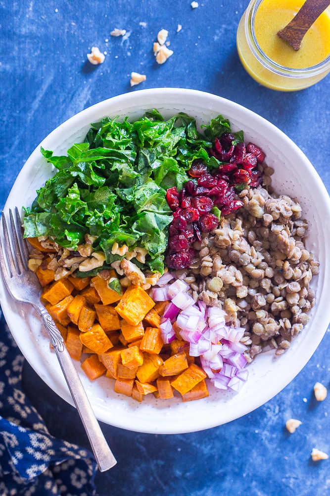 Kale Salad with Sweet Potato and Lentils in a bowl with a side of dressing