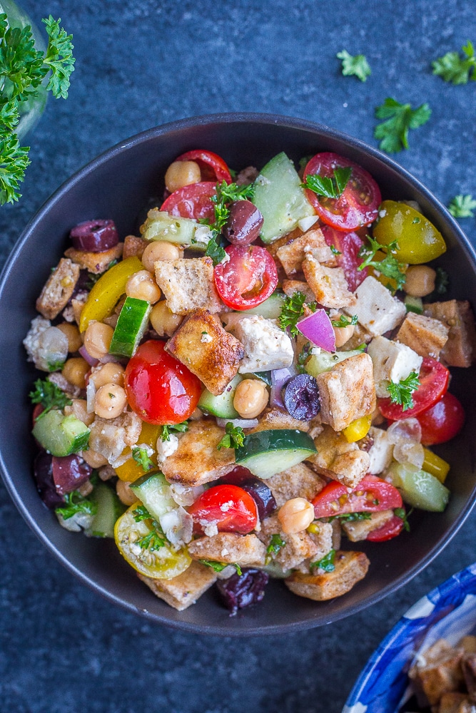 A bowl of Greek Chopped Salad with Crispy Pita on a black background