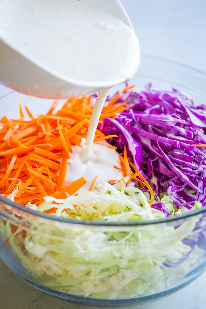 Dressing being poured over easy homemade coleslaw