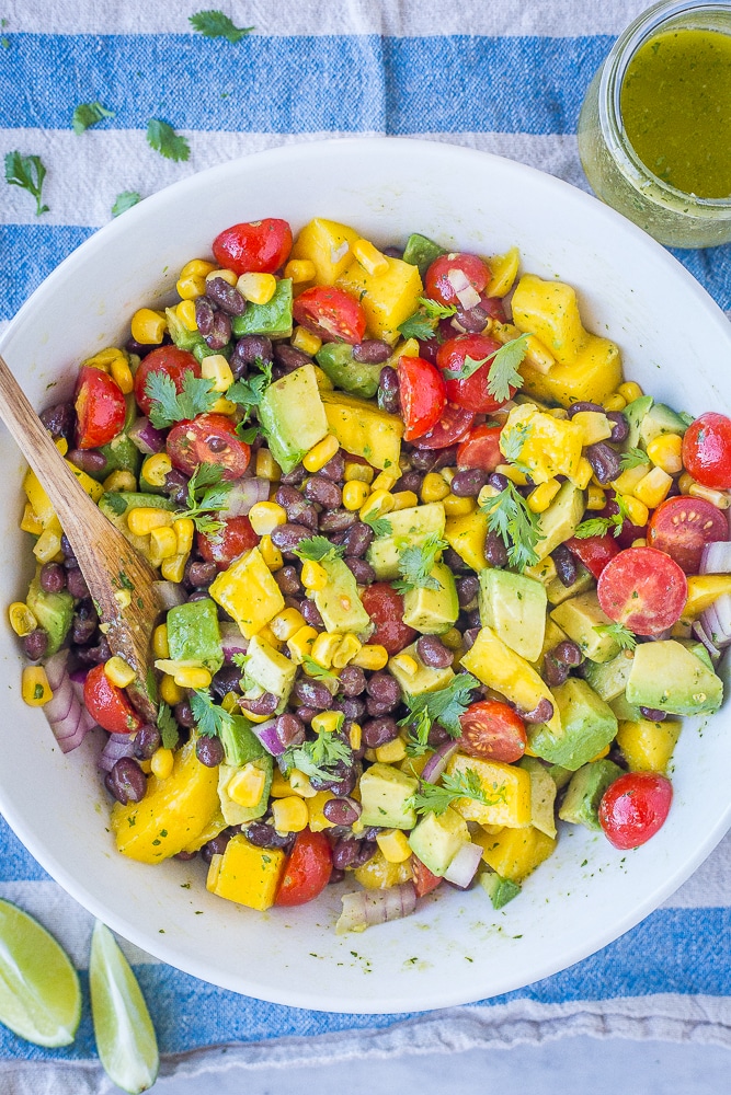 Black Bean Salad with Mango and Avocado in a white bowl on a blue striped napkin