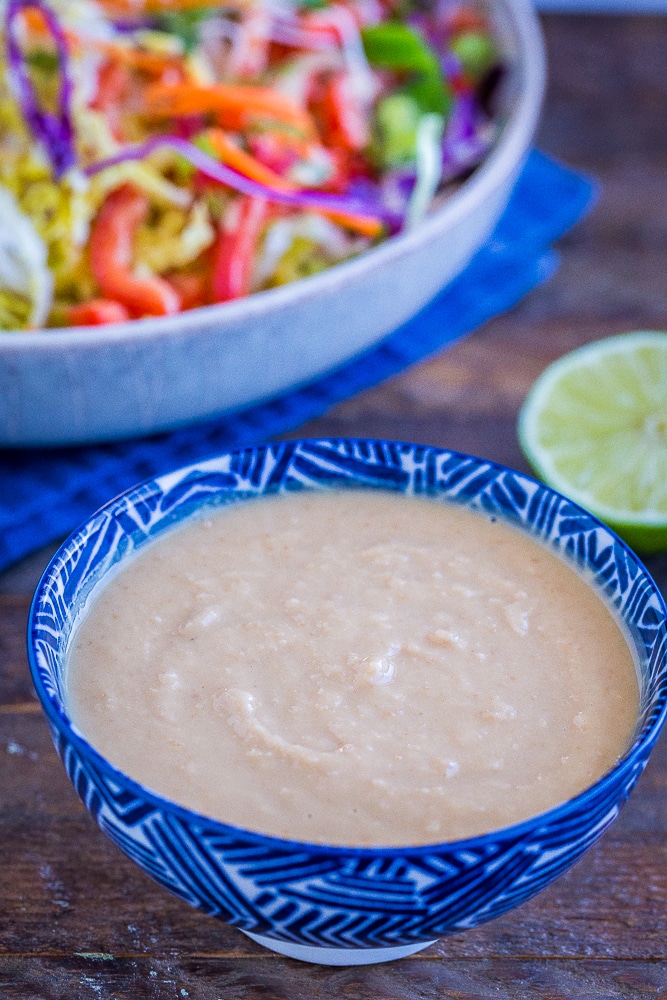Best homemade peanut sauce in a bowl with a salad in the background