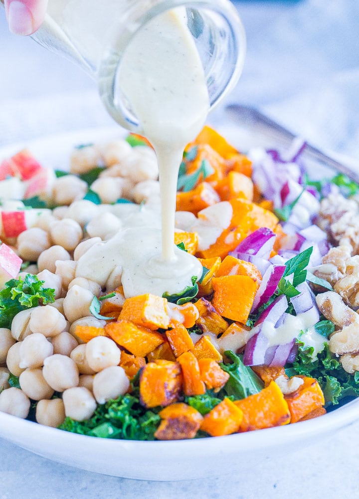 Close up of pouring creamy apple cider vinegar dressing on fall harvest salad