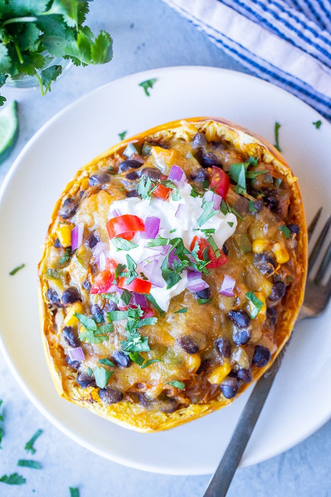 These Spaghetti Squash Enchilada Boats are so easy to make! They're super hearty and filling, packed with veggies and protein and perfect for a vegetarian dinner that the whole family will love! Each half only has 7 Freestyle Weight Watchers points! #spaghettisquash #spaghettisquashboat #enchilada #weightwatchers #vegetarian