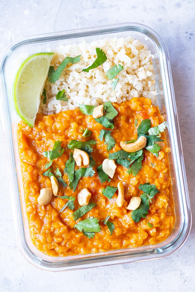 Red lentil curry in a meal prep container with cauliflower rice