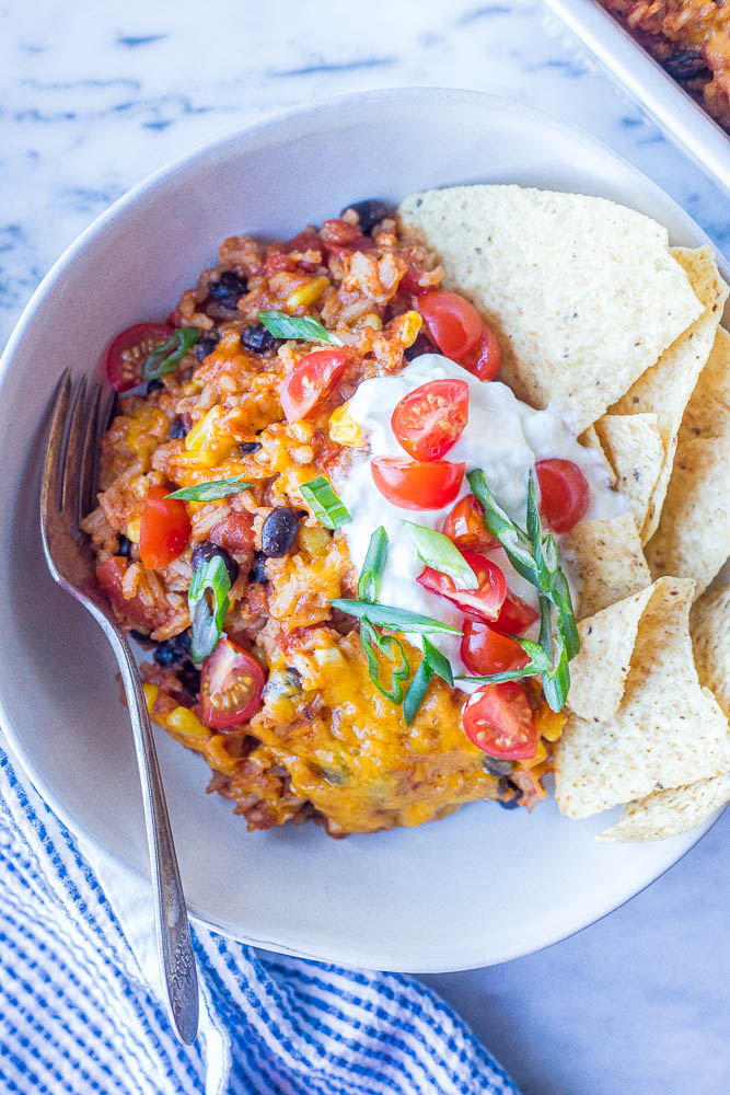 Close up of a bowl of enchilada rice casserole with toppings