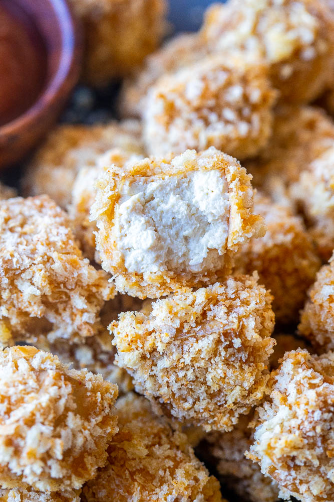 Close up of a crispy tofu nugget with a bite taken out of it