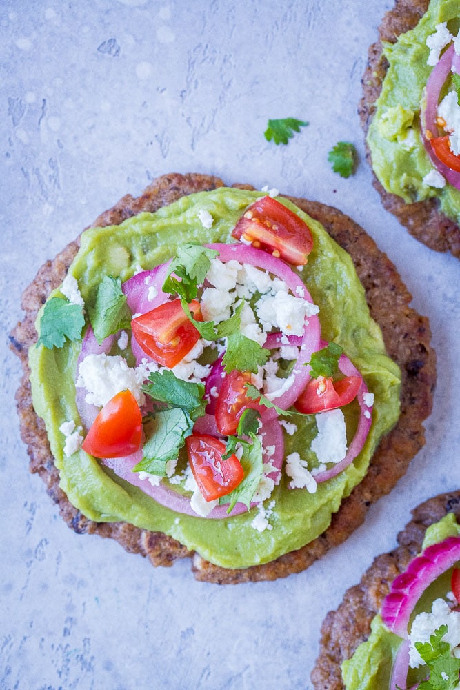 Close up of a guacamole tostada with a black bean tortilla