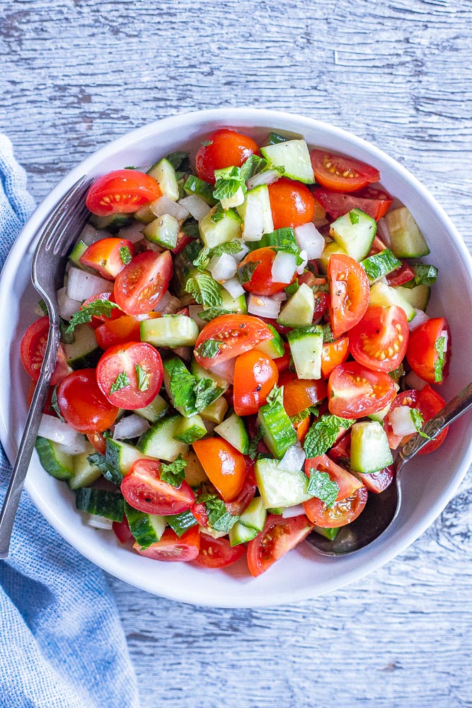 Big bowl of cucumber tomato salad with fresh herbs