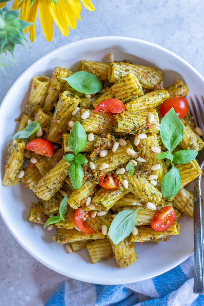 Bowl of sun-dried tomato pesto pasta with a sunflower and napkin