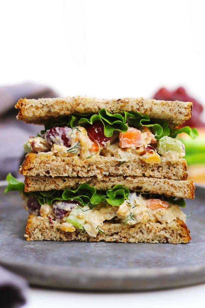 A close up of a sandwich on a plate, with Salad and Bread