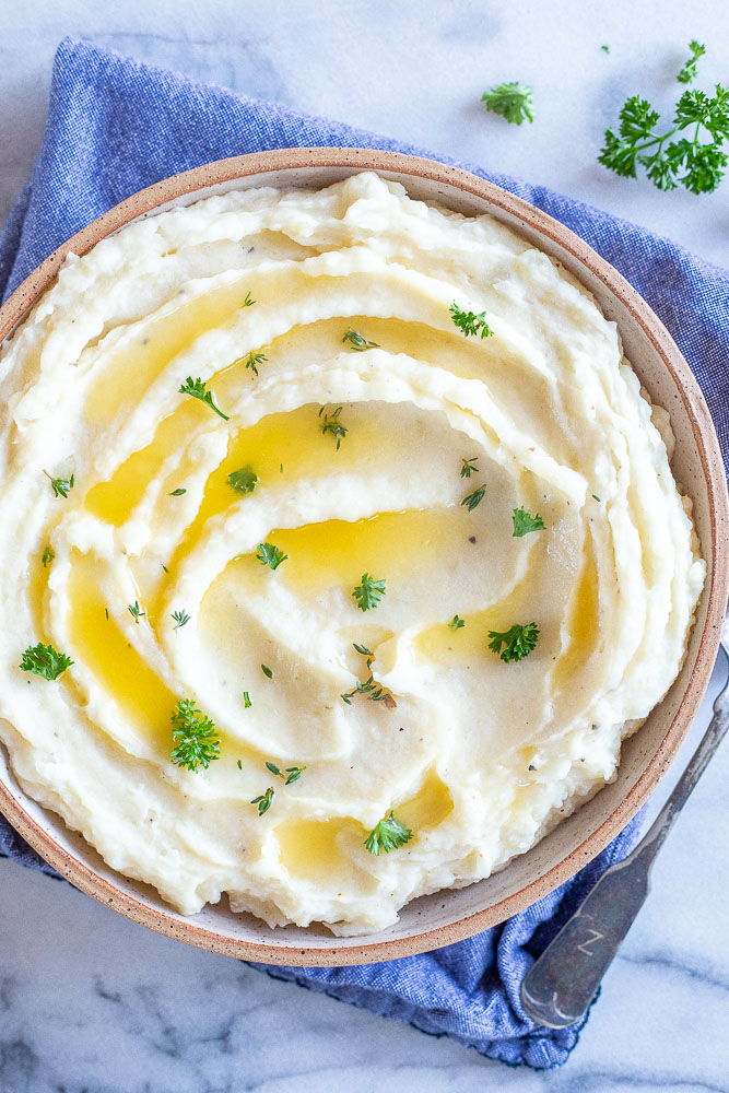 mashed potatoes in a bowl swirled with butter and fresh herbs