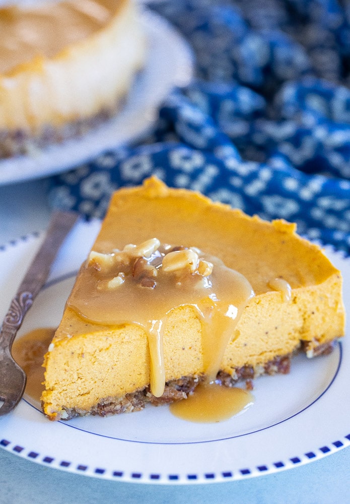 Close up of a slice of vegan pumpkin cheesecake with caramel on top