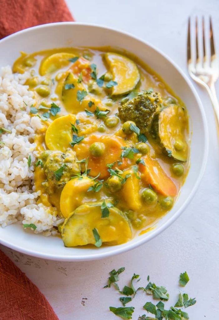 A bowl of food on a plate, with Curry and Pumpkin