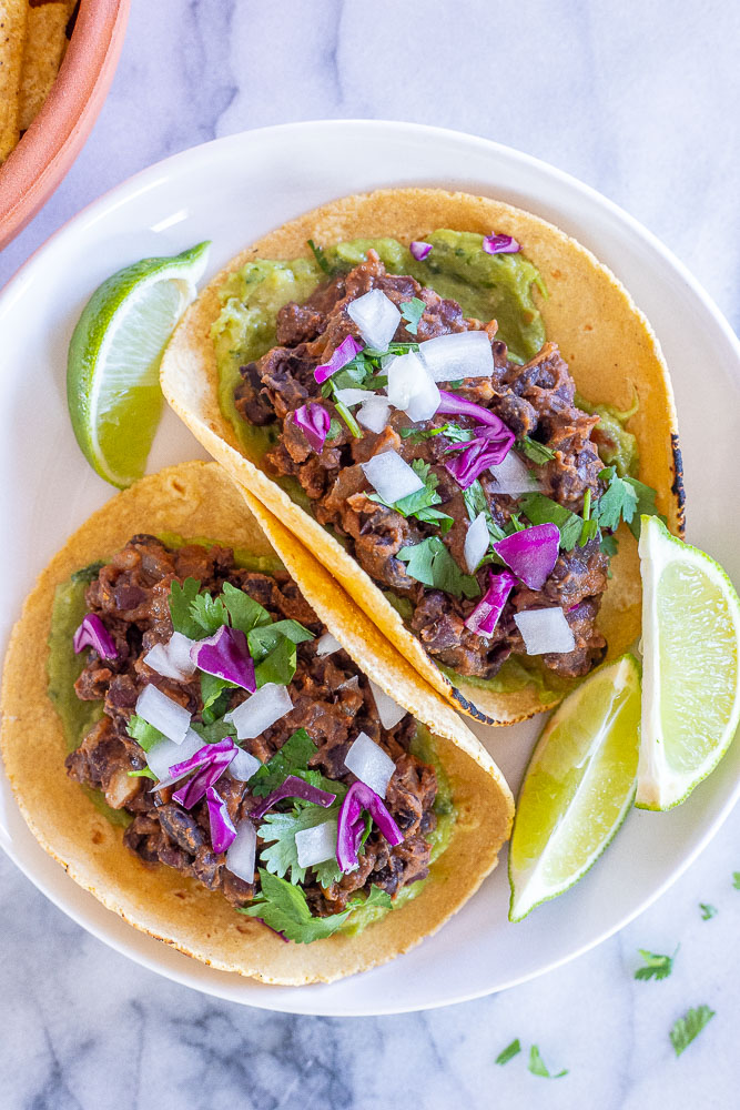 two black bean tacos on a plate with toppings